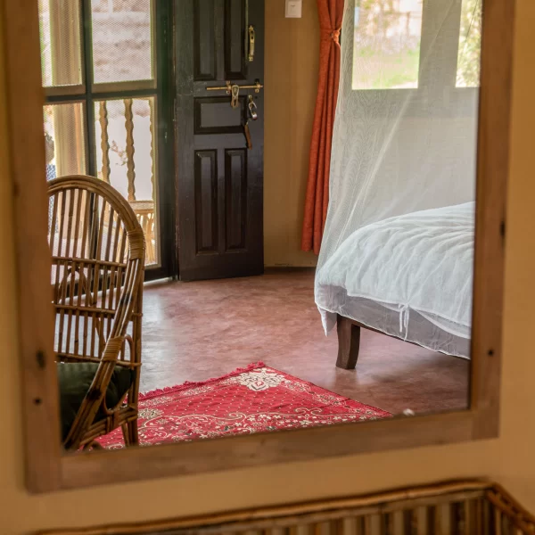 Reflection of the room through the large mirror. Spacious room with big windows and rattan furnitures