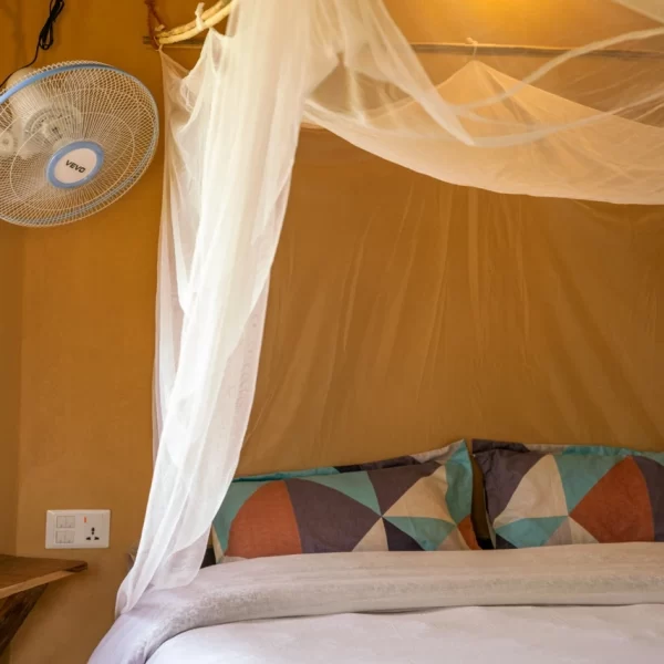 Double bed with mosquito net and wall fan