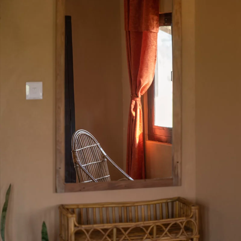 View of the room through the mirror, with rattan furnitures, indoor plant and window