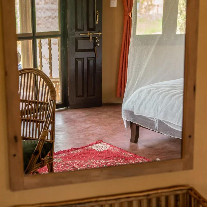 Reflection of the room through the large mirror. Spacious room with big windows and rattan furnitures